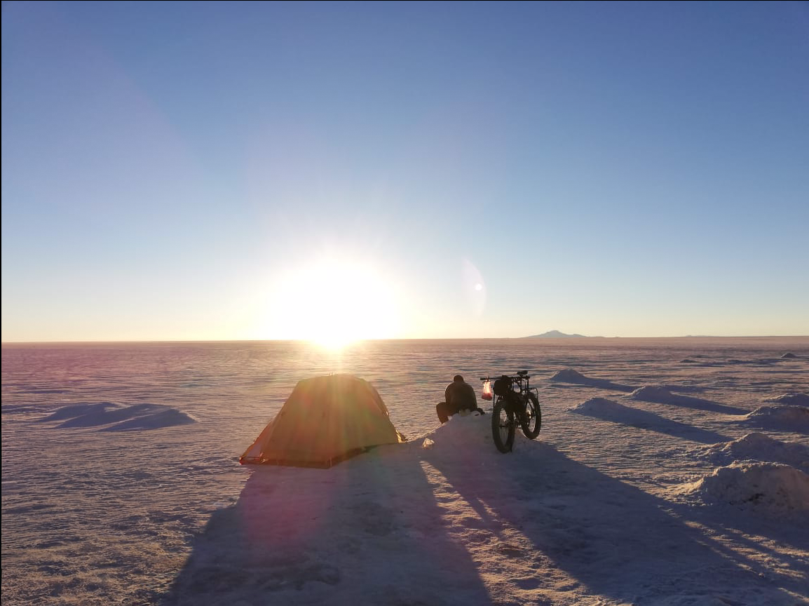 Tent and loaded bicycle at sunrise on the salt flat